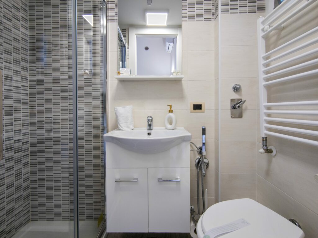 Bagno moderno con doccia, lavandino bianco e piastrelle decorate
